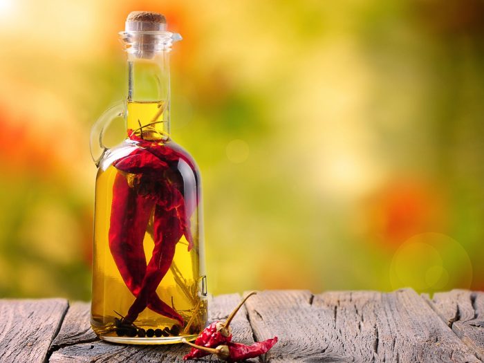 Close up of a chili oil bottle, infused with whole chilis and black pepper