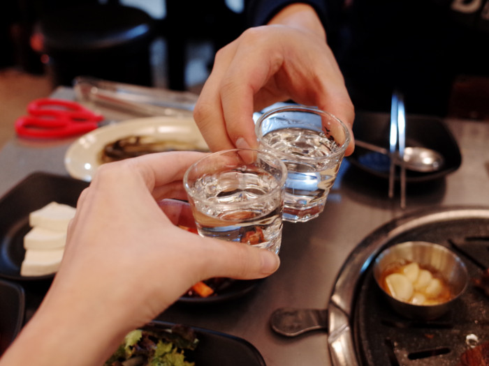 Two shots of soju in glasses being held